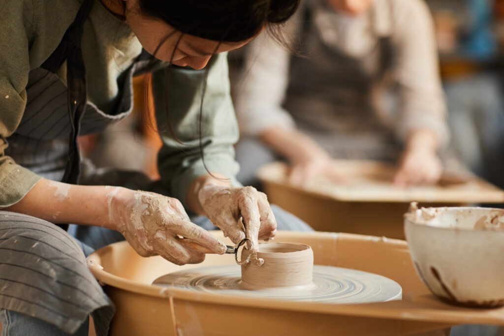 Hands shaping pottery on a wheel