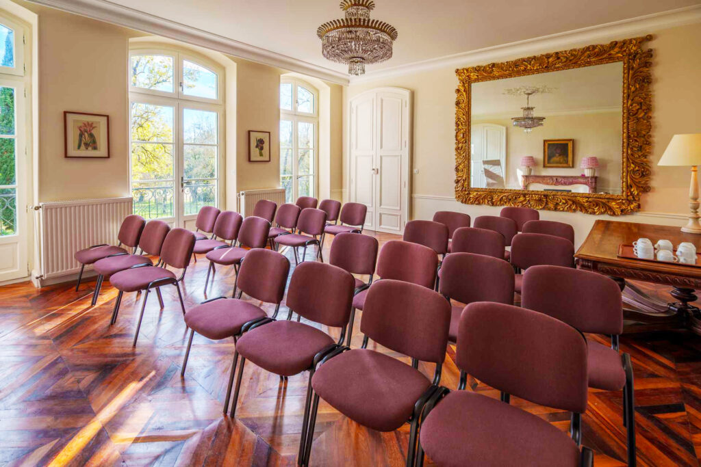 Salle de séminaire lumineuse avec rangées de chaises au château