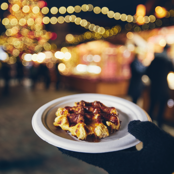 Waffle held in front of the lights at a Christmas market