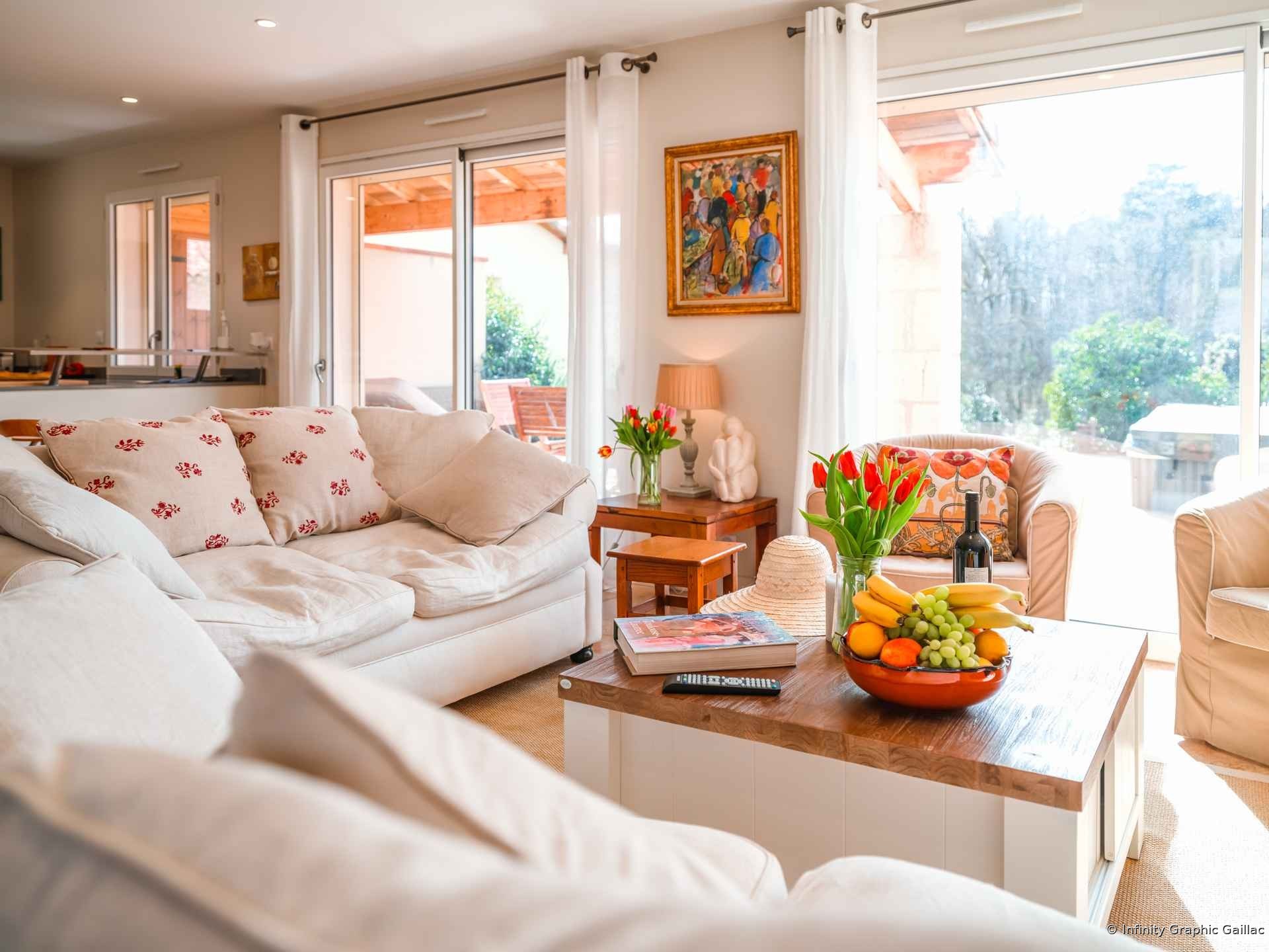 Salon lumineux d’une villa avec canapé et grandes fenêtres