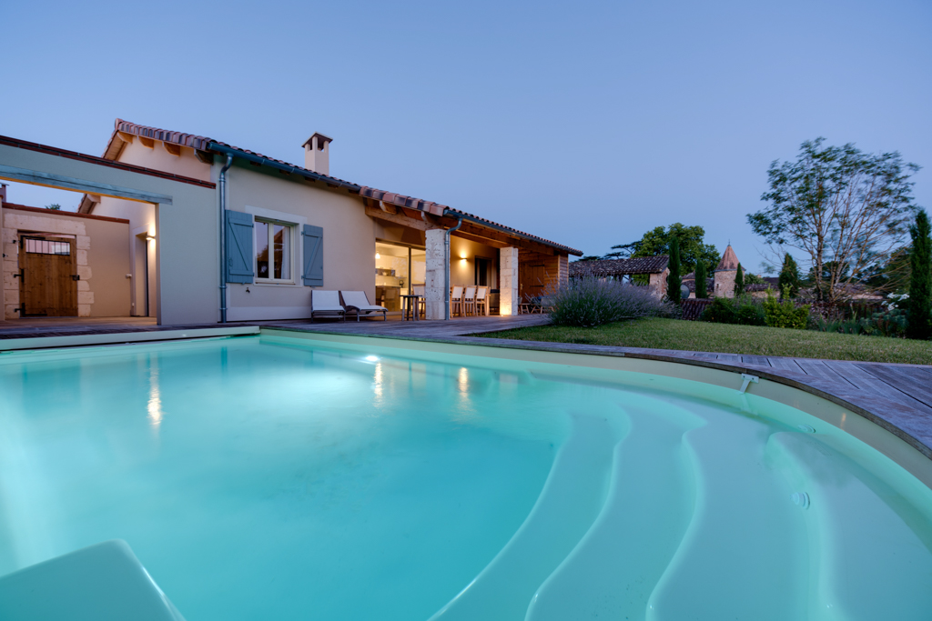 Piscine éclairée devant une villa au crépuscule